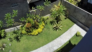 A residential area with a house featuring a tiled roof and a concrete wall. There is a well-maintained lawn with various shrubs and a pathway. - Bali Fab Dive Center - Hostel (Karangasem)