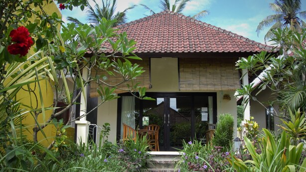 A house with a tiled roof, a wooden staircase leading to a glass door, and a garden with various plants and flowers. - Bali Fab Dive Center - Hostel (Karangasem)
