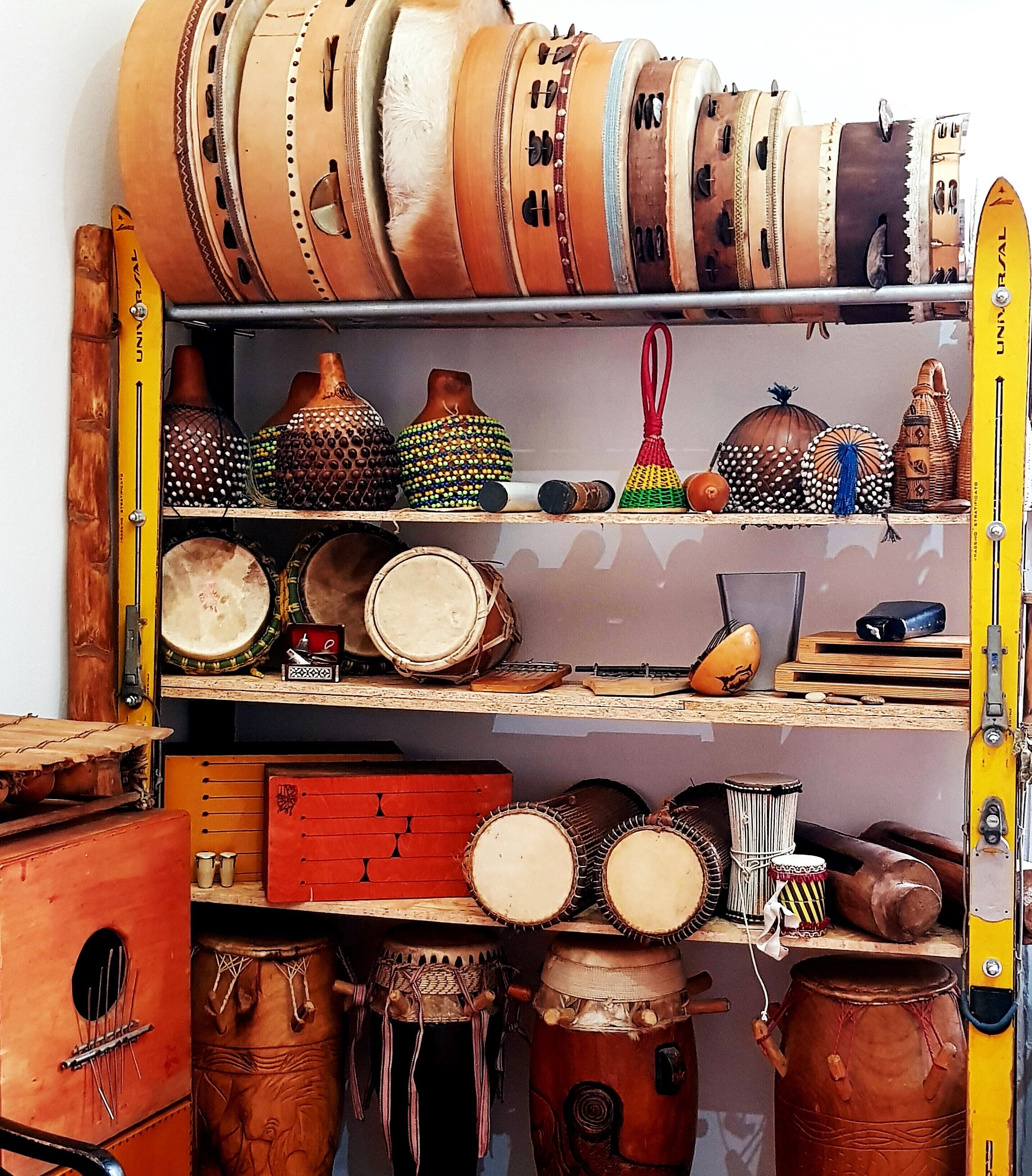 A storage room with shelves holding various drums and musical instruments.