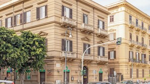 Un edificio de varios pisos con balcones, una farola y un semáforo.