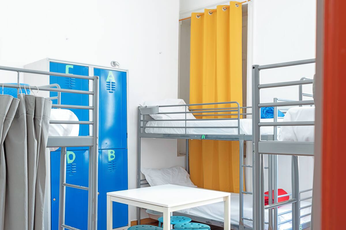 Ein Schlafsaalzimmer mit Etagenbetten, einem Tisch und Ablackerschränken.