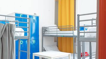 Ein Schlafsaalzimmer mit Etagenbetten, einem Tisch und Ablackerschränken.