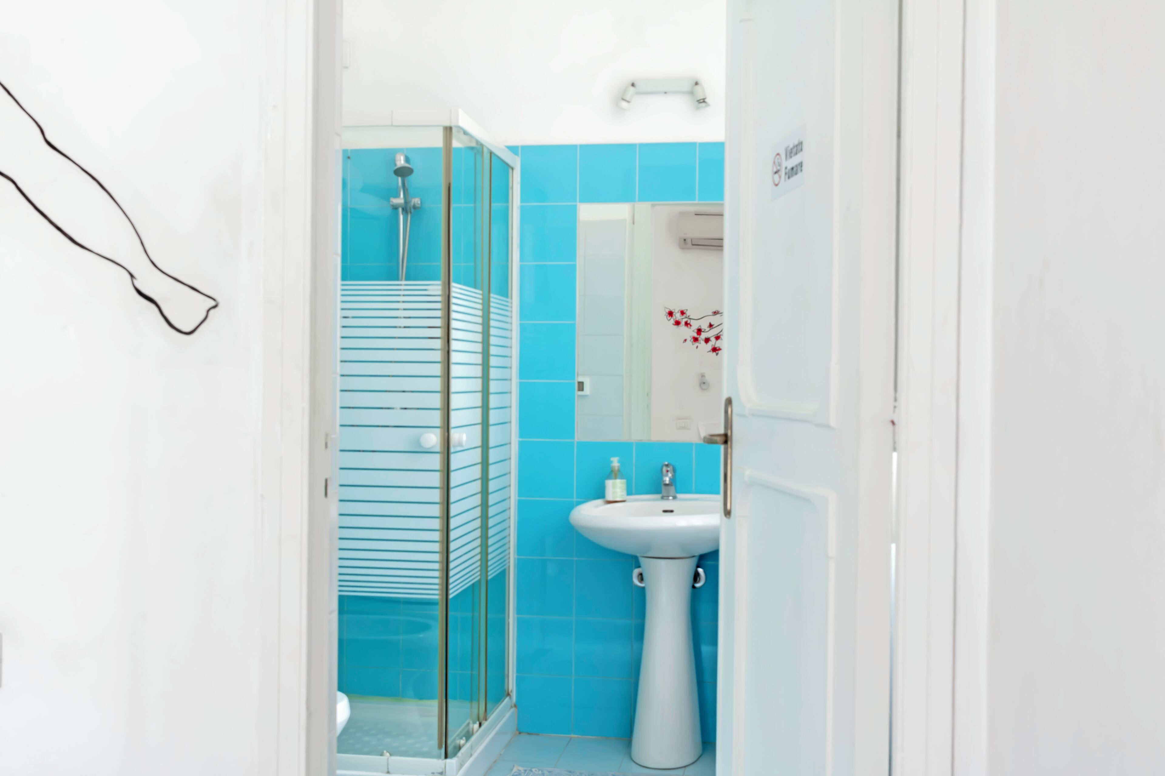 Un baño con cabina de ducha de vidrio, un lavamanos blanco y azulejos azules.