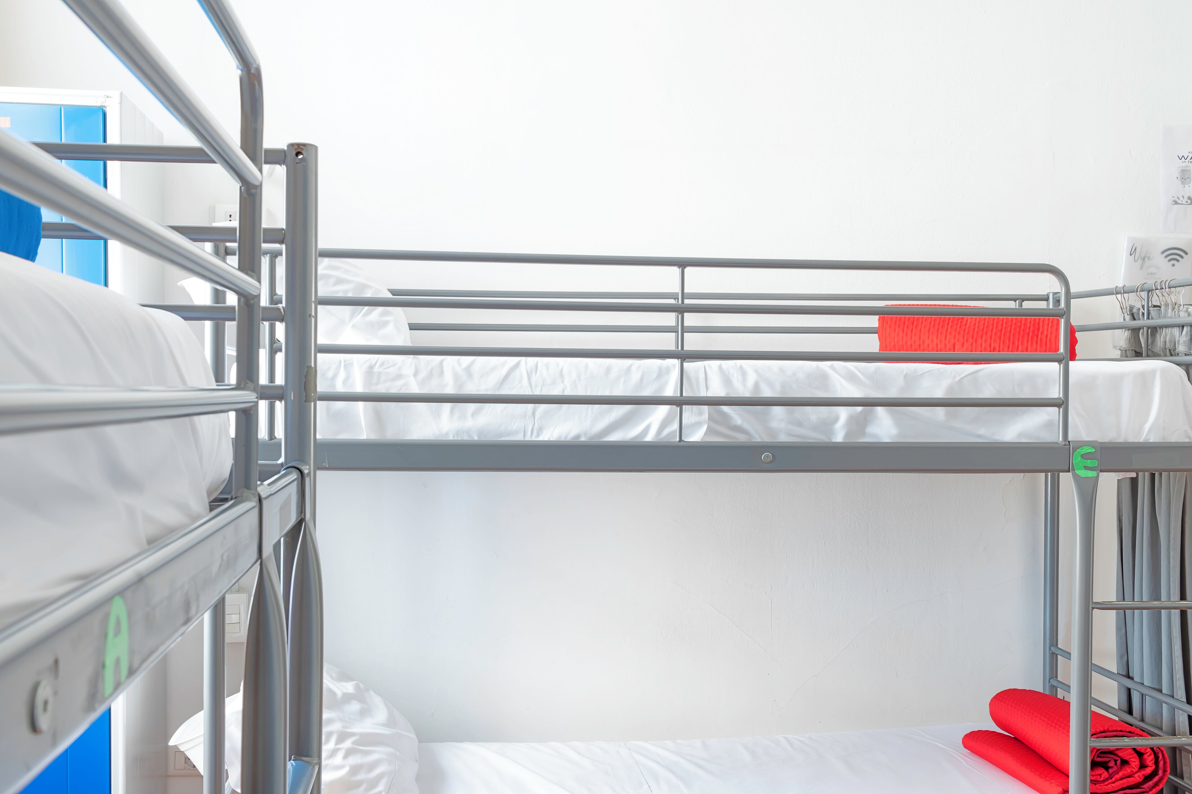 A bunk bed with metal railings, white bedding, and a red towel on the top bunk.