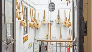 Una habitación con instrumentos de cuerda tradicionales colgados en la pared, una ventana con vistas y una puerta con un letrero.