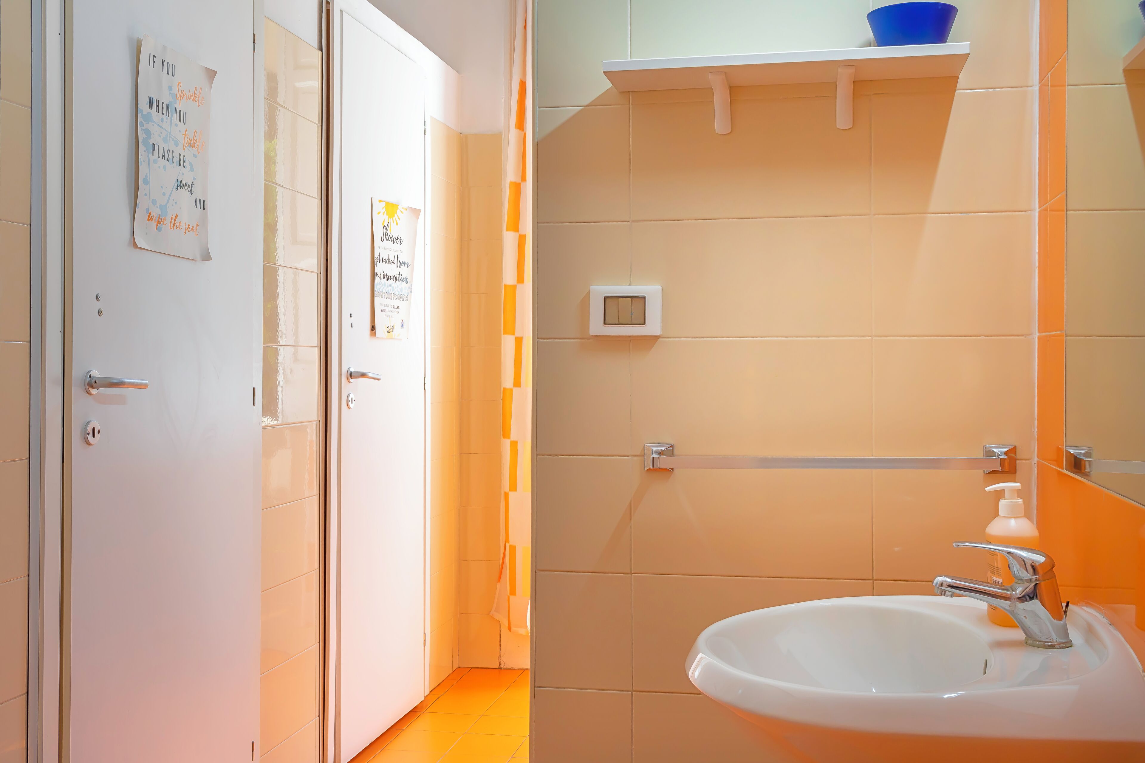 A bathroom with a white sink, a mirror, and a blue bowl on a shelf.