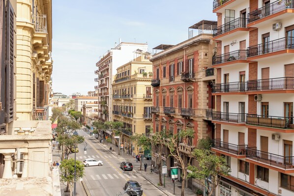 Vista de una calle en una ciudad con edificios de varios pisos, algunos con balcones y otros con comercios a nivel de calle.