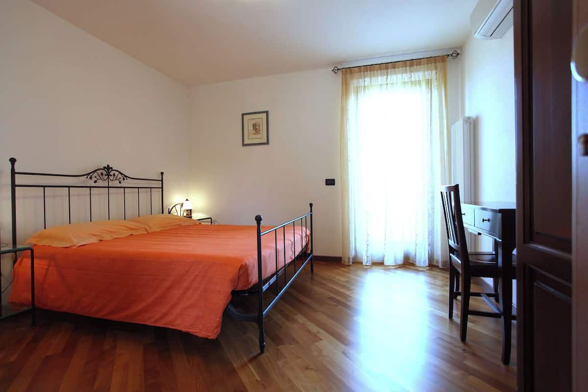 A bedroom with a bed, a desk, and a chair.