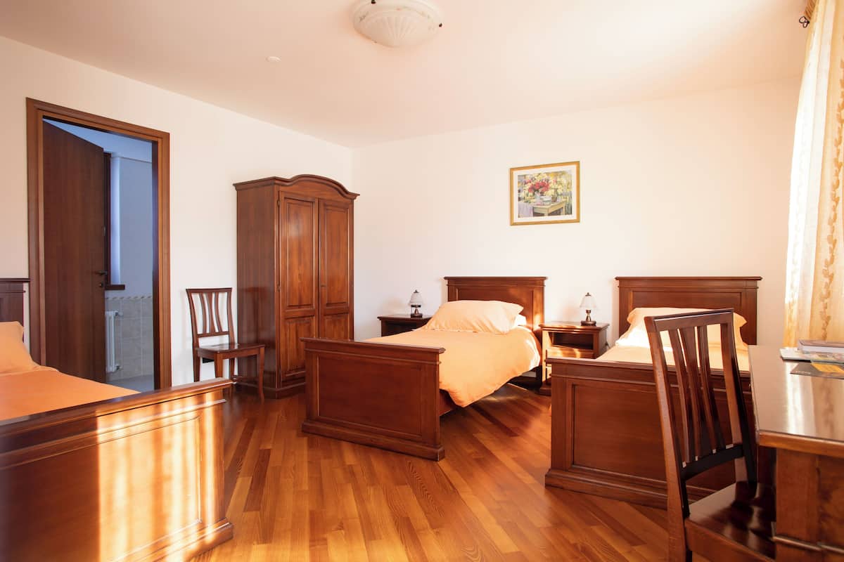 A bedroom with a wooden bed, nightstands, a wardrobe, and a chair.