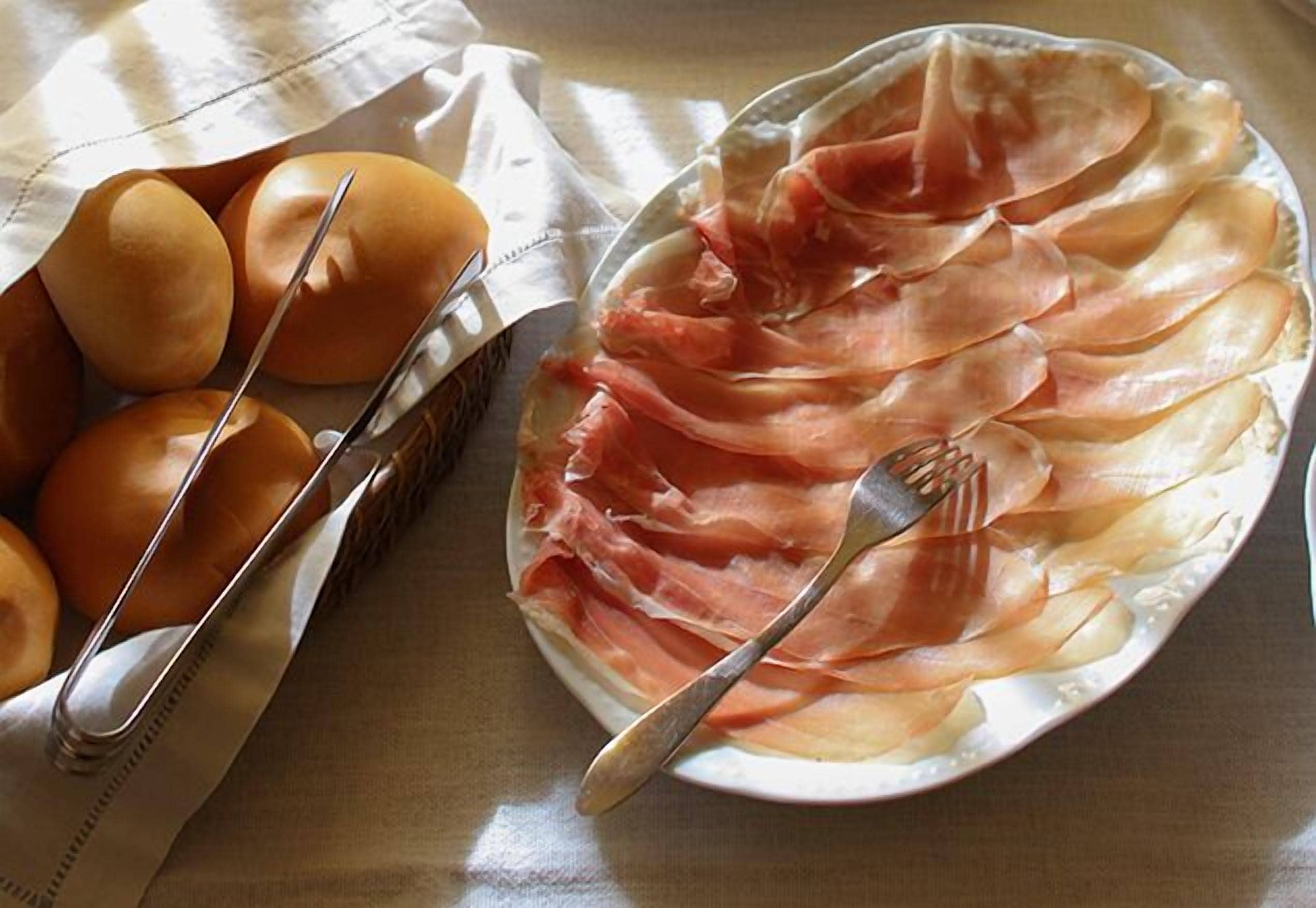 A plate of prosciutto and eggs on a table.