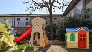 Une aire de jeux avec un toboggan et une petite maison de jeu.