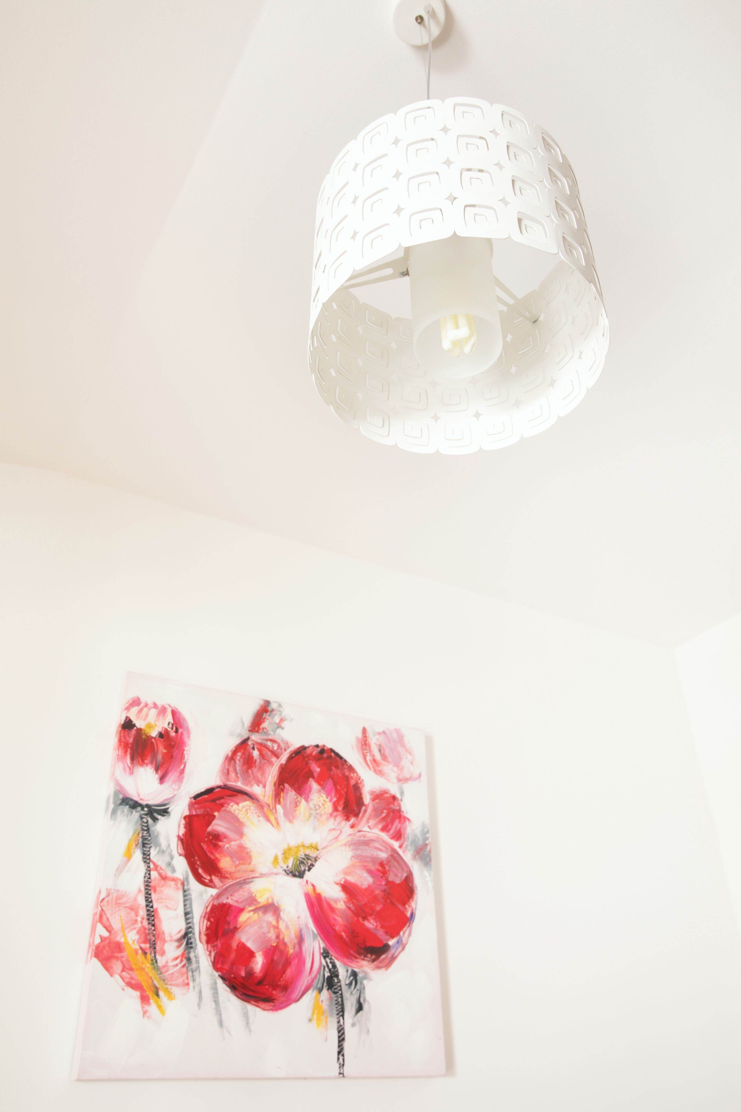 A white ceiling with a textured light fixture and a floral painting below.