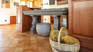 Une pièce avec une table en pierre, un panier en osier contenant des sacs et un tabouret en pierre.