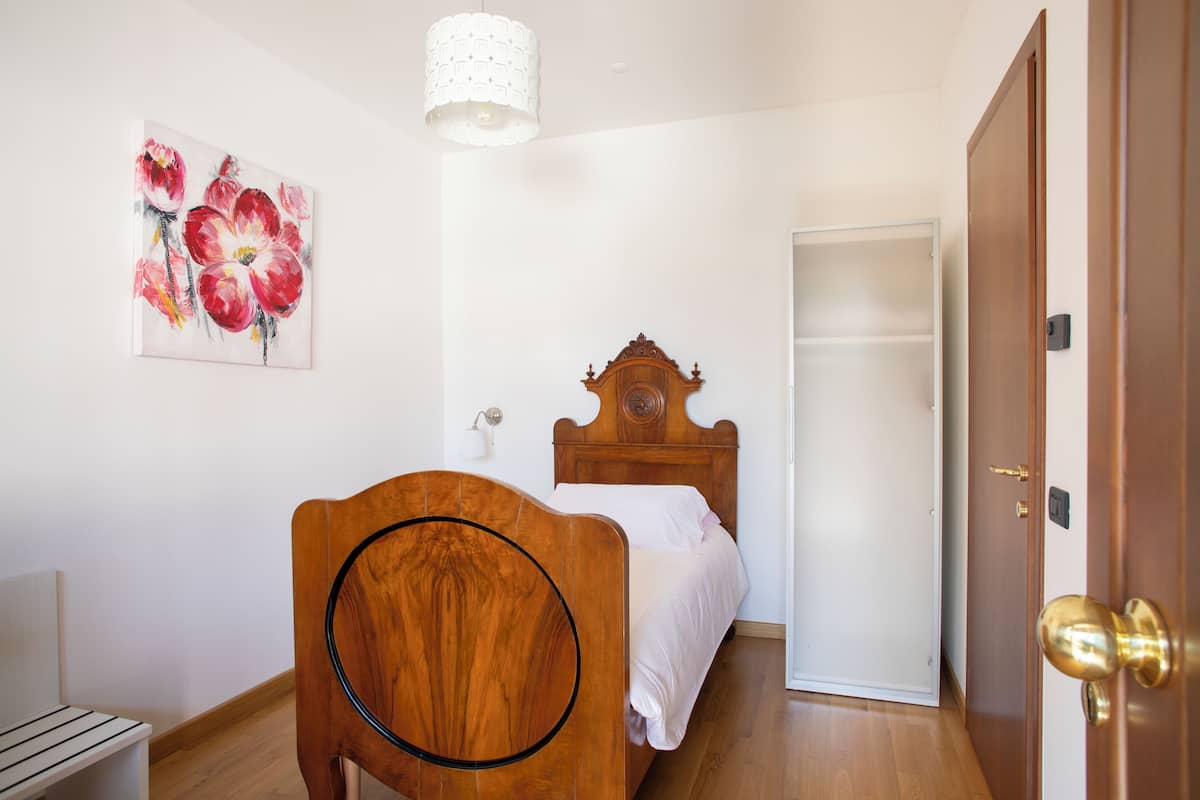 A bedroom with a wooden bed, a white wall, and a door.