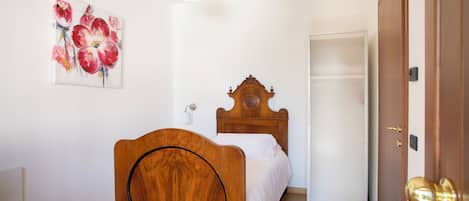 A bedroom with a wooden bed, a white wall, and a door.