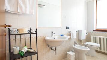 Une salle de bain équipée d’un lavabo, d’un bidet, de toilettes et d’un miroir.
