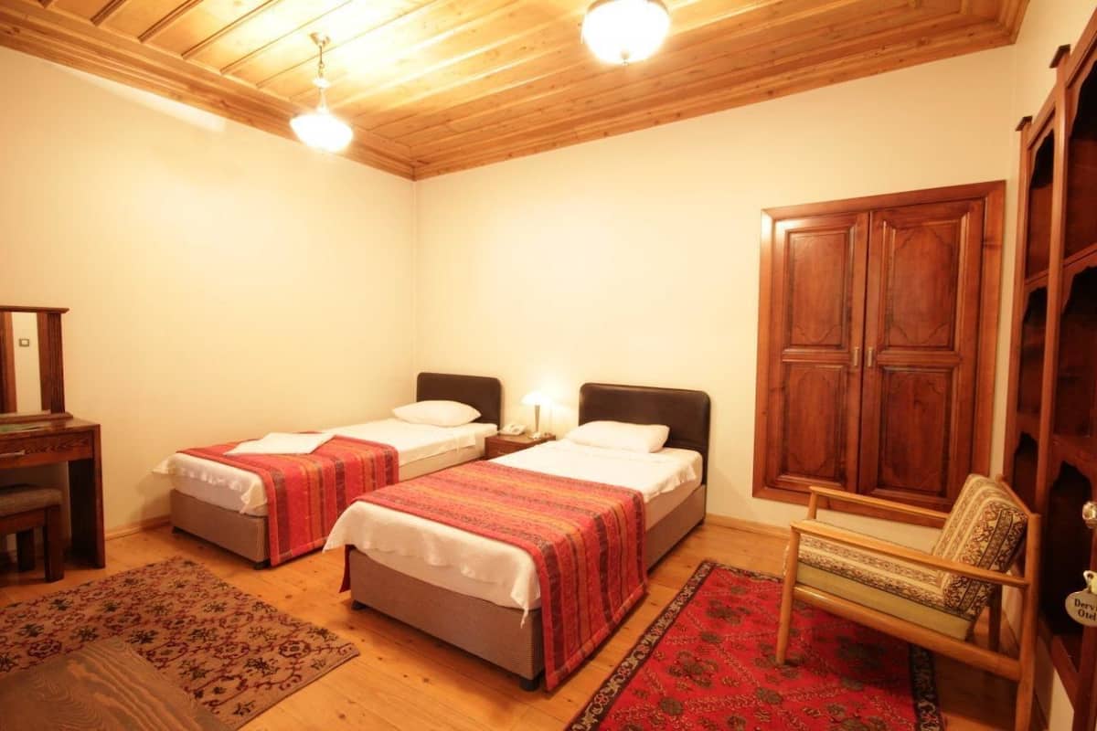 Una habitación con dos camas, techo de madera, un escritorio, una silla y un armario.