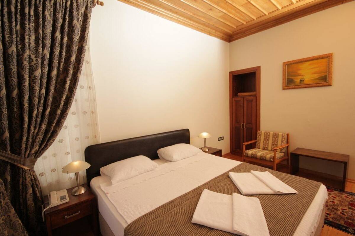 Habitación de hotel con cama, una silla, un escritorio y un cuadro en la pared.