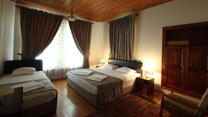 A hotel room with a wooden ceiling, two beds, a nightstand, a wardrobe, and a patterned rug. - Konya Dervish Hotel (Konya)