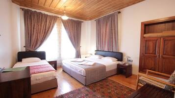 Un dormitorio con dos camas, techo de madera, un armario grande y un tapete estampado.