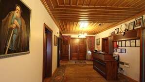 A hallway with wooden paneling, a reception desk, framed certificates, and a large portrait on the wall. - Konya Dervish Hotel (Konya)