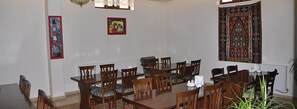 A dining room with a long wooden table and chairs, a chandelier, and two framed artworks on the walls. - Konya Dervish Hotel (Konya)