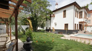A garden with a pergola, a pool, and a white building with brown trim. - Konya Dervish Hotel (Konya)