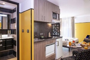 Una habitación de hotel funcional con kitchenette, zona de comedor y sala de estar.