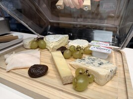 A variety of cheeses and grapes on a wooden board.