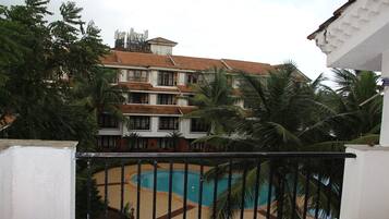 A multi-story building with a swimming pool surrounded by palm trees.