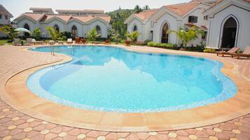 Una piscina al aire libre, sillones reclinables de piscina