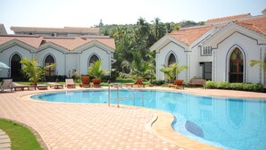 A swimming pool with lounge chairs and a tiled deck. - Riviera Hermitage (Arpora)