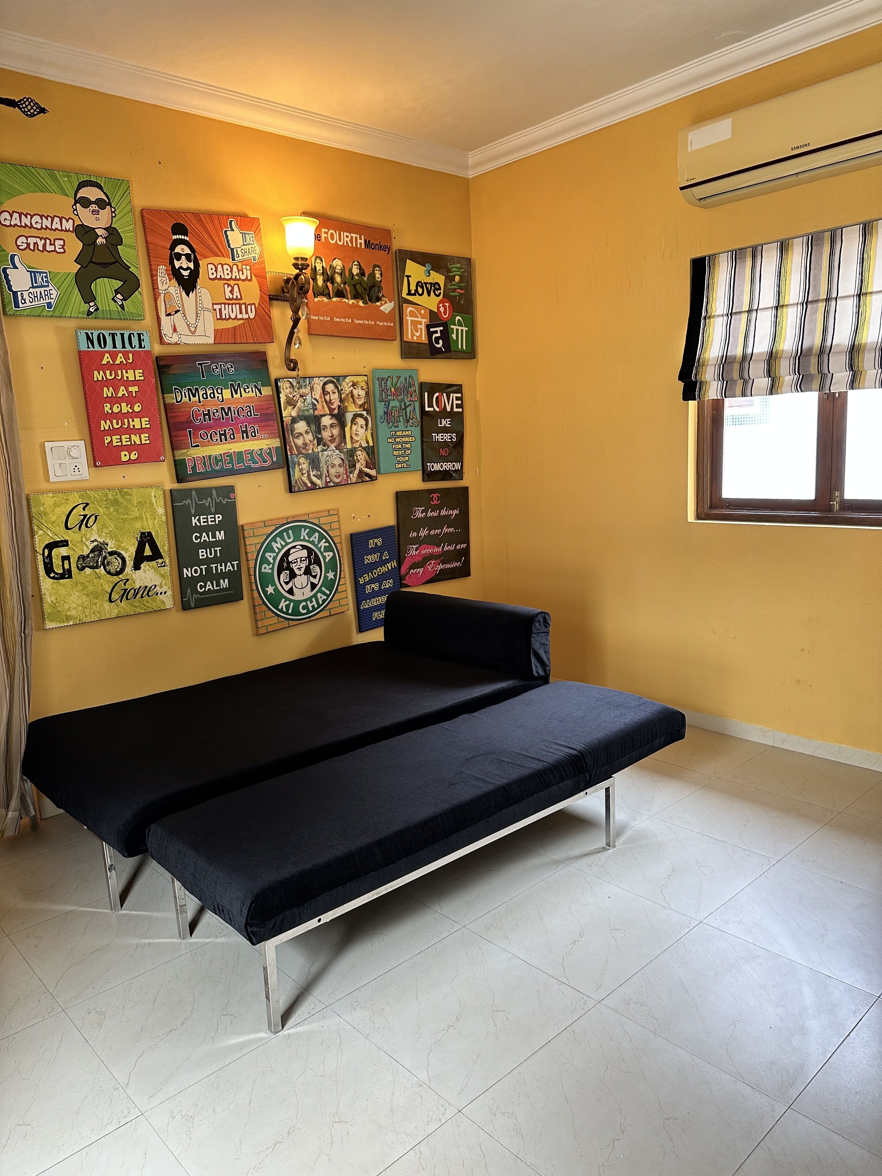 A room with a bed, a window with striped curtains, and a wall decorated with various posters.