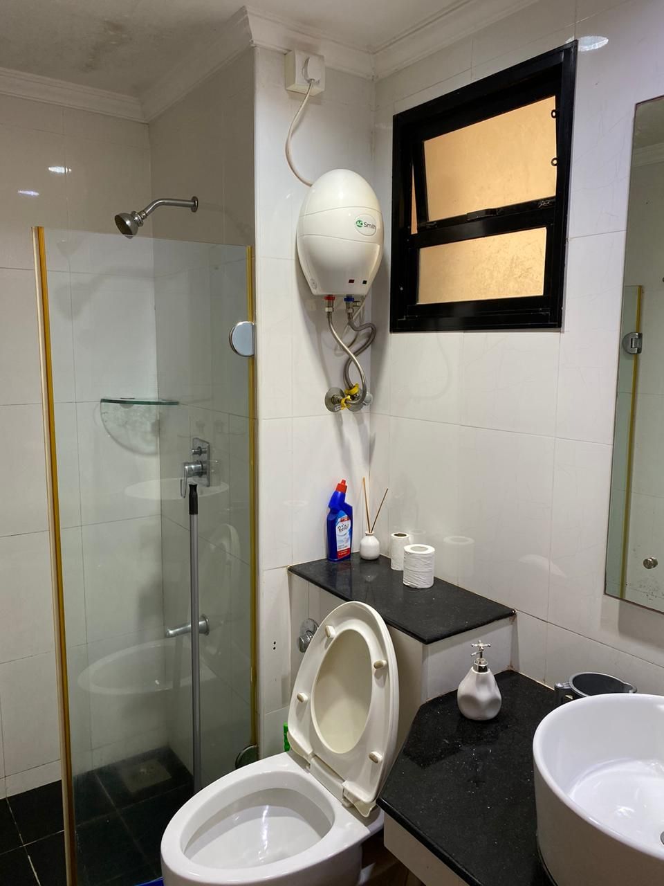 Ein Badezimmer mit einer Duschkabine, einer Toilette, einem Waschbecken und einem an der Wand montierten Händetrockner.