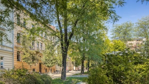 A tree-lined street with buildings on either side, a clear sky, and a sidewalk. - Old Town Residence BIS (Kraków)