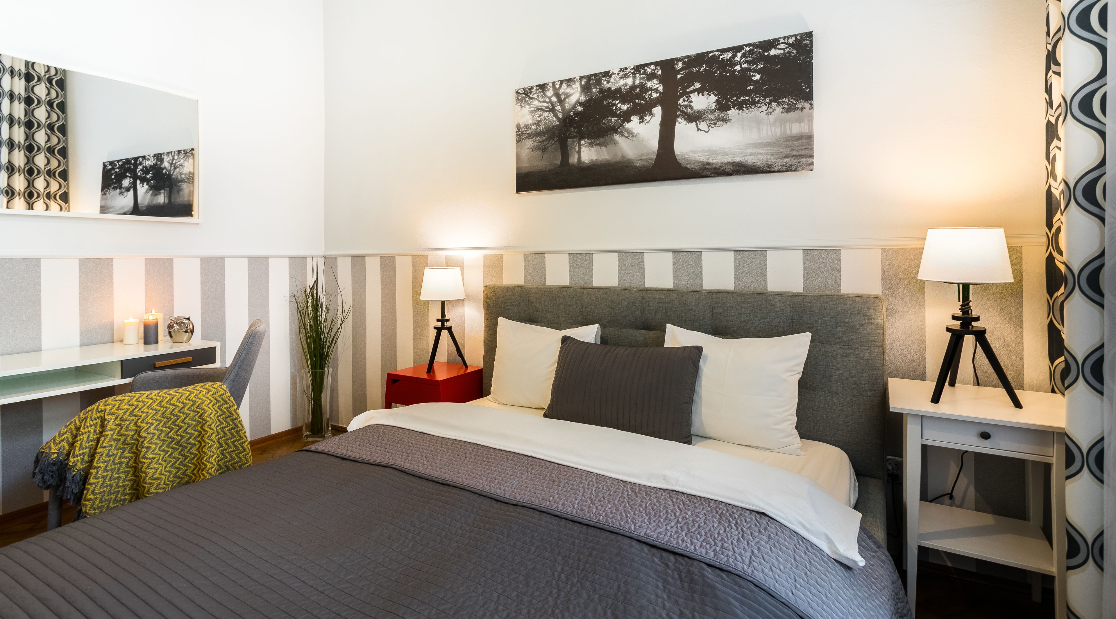 A neatly arranged hotel room with a bed, bedside tables, a desk, and a chair.
