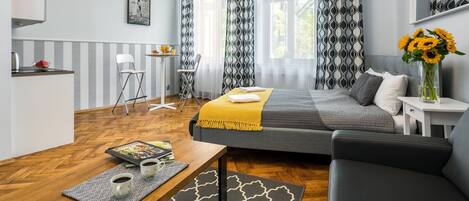 Un dormitorio moderno con cama, sofá, mesa de comedor y una pequeña cocina.