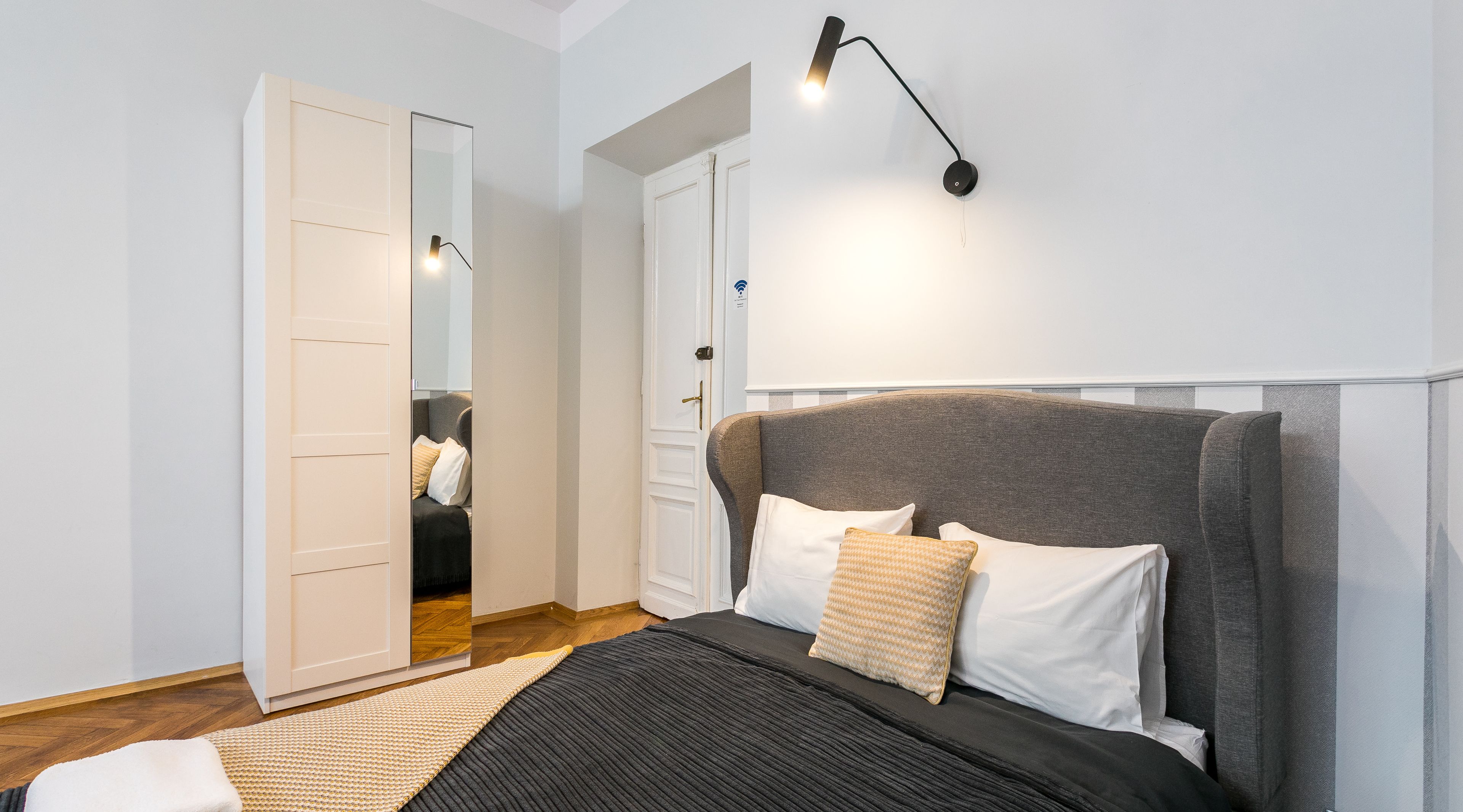 A bedroom with a bed, bedside table, lamp, and wardrobe.