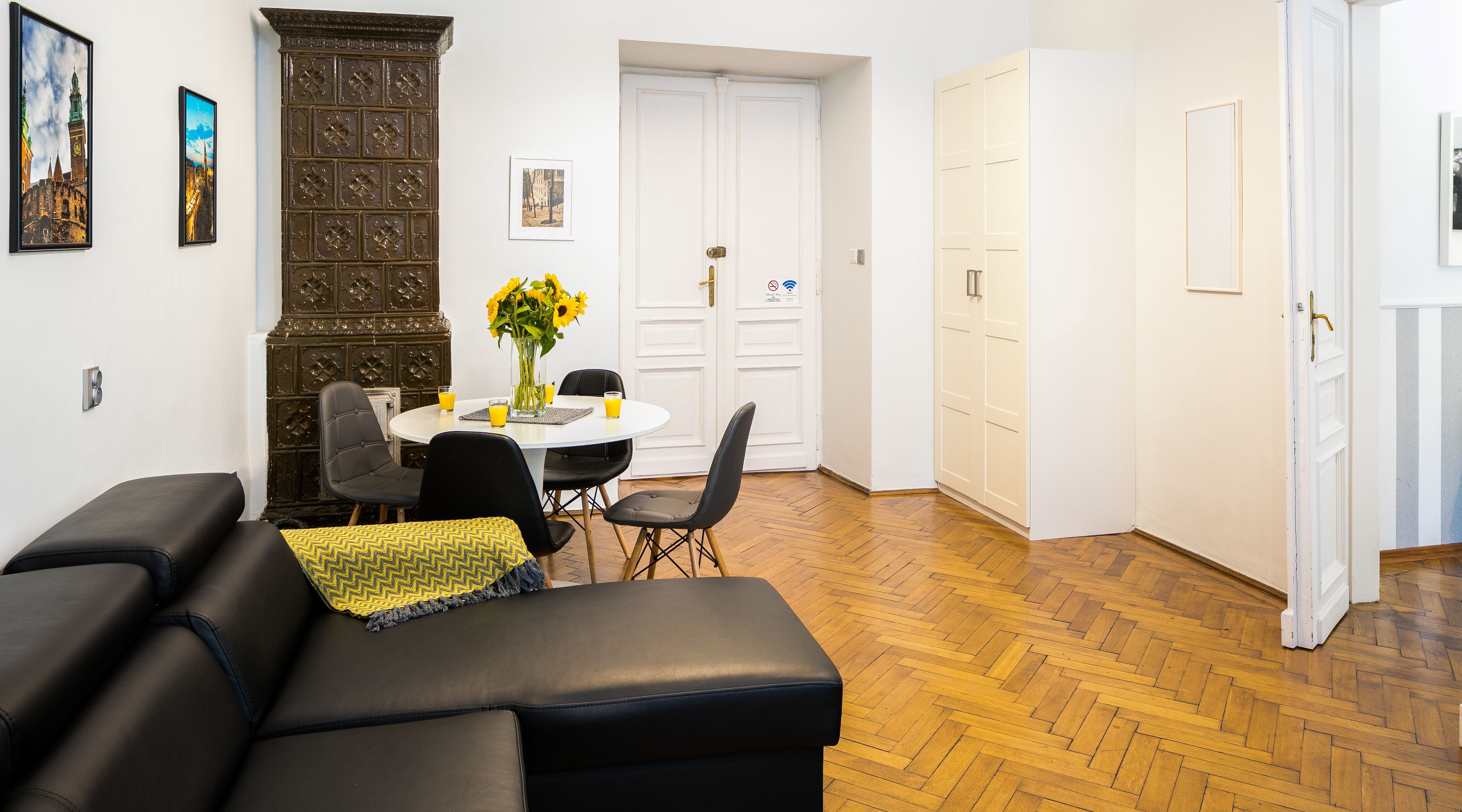 Un salon avec un canapé en cuir noir, une table à manger avec des chaises et un grand meuble en bois.