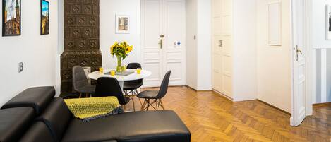 Un salon avec un canapé en cuir noir, une table à manger avec des chaises et un grand meuble en bois.