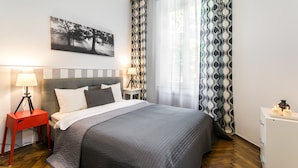 A neatly arranged bedroom with a bed, bedside tables, a lamp, and a painting on the wall. - Old Town Residence BIS (Kraków)