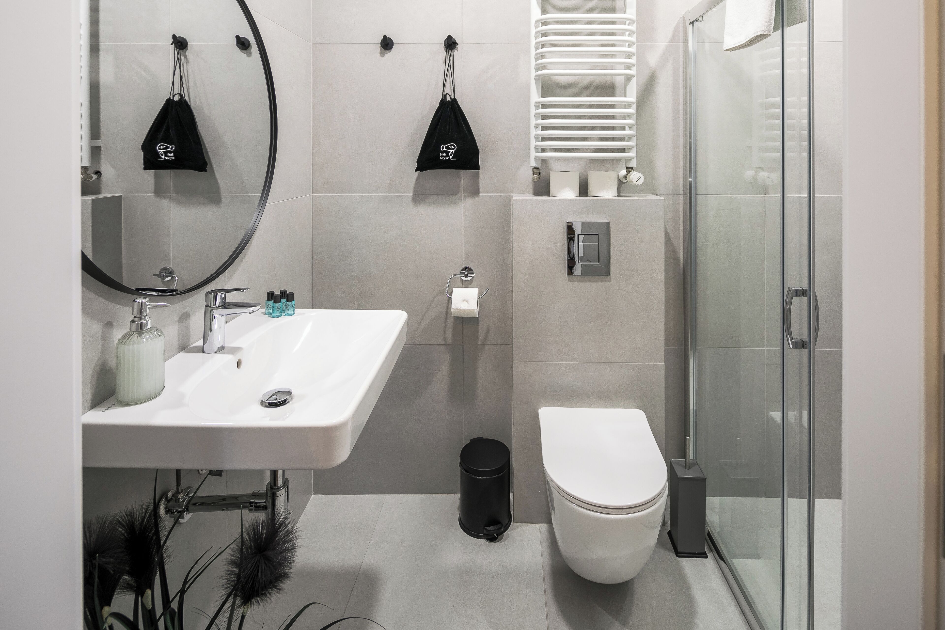 A modern bathroom with a white sink, a toilet, and a glass shower enclosure.