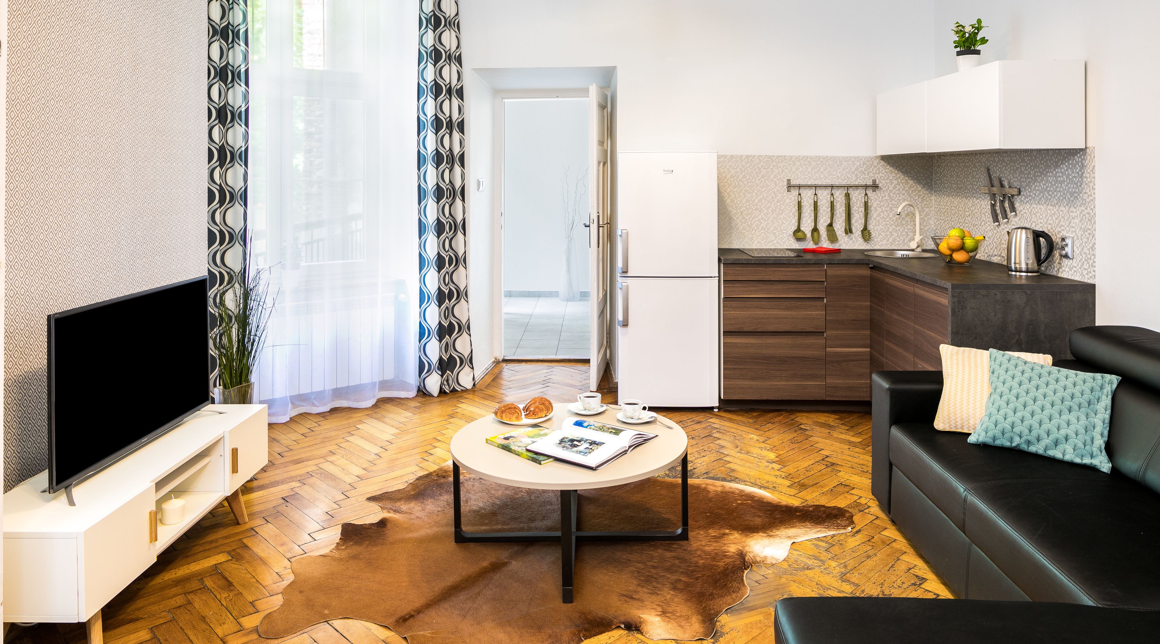 Un salon moderne avec un téléviseur à écran plat, une table basse sur laquelle est posé un magazine et un canapé en cuir.