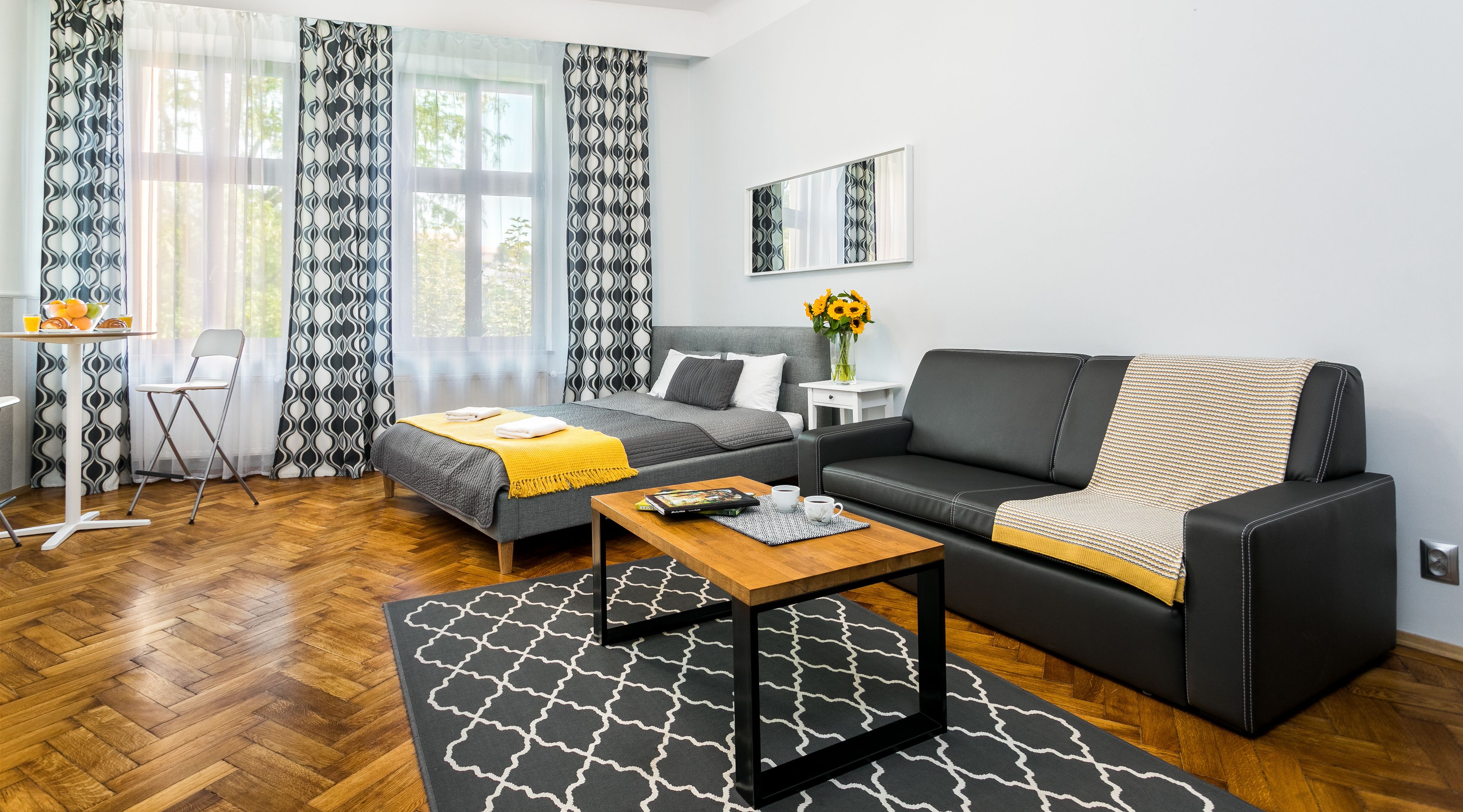 A modern living room with a sofa, a bed, a dining table, and a coffee table.