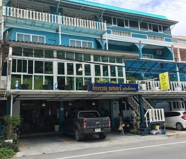 A multi-story building with a blue and white facade, a signboard, and a parked truck. - I Talay Lodge Boutique Hotel (Rayong)