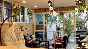 A cozy indoor seating area with a wooden table, black leather sofa, and a hanging chair. - I Talay Lodge Boutique Hotel (Rayong)