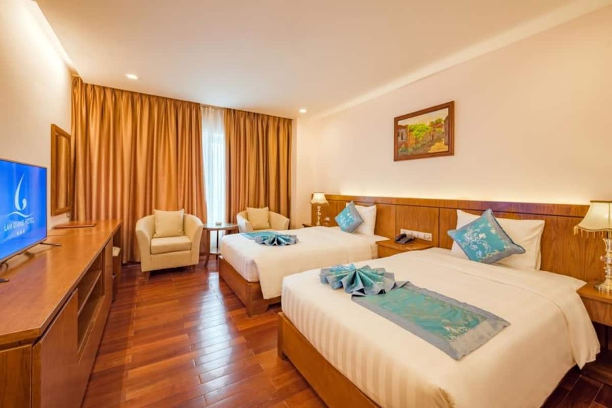 A hotel room with two beds, a TV, a desk, and a chair.