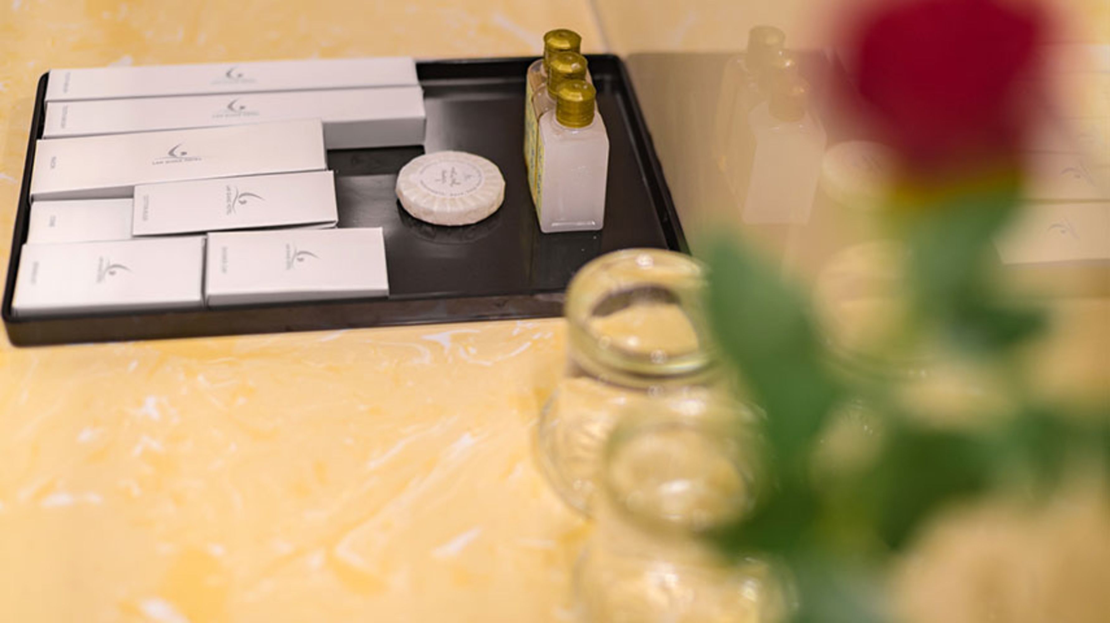Una bandeja con varios artículos de tocador, como una botella de loción, un pequeño recipiente y varias cajas, probablemente para productos de higiene personal.
