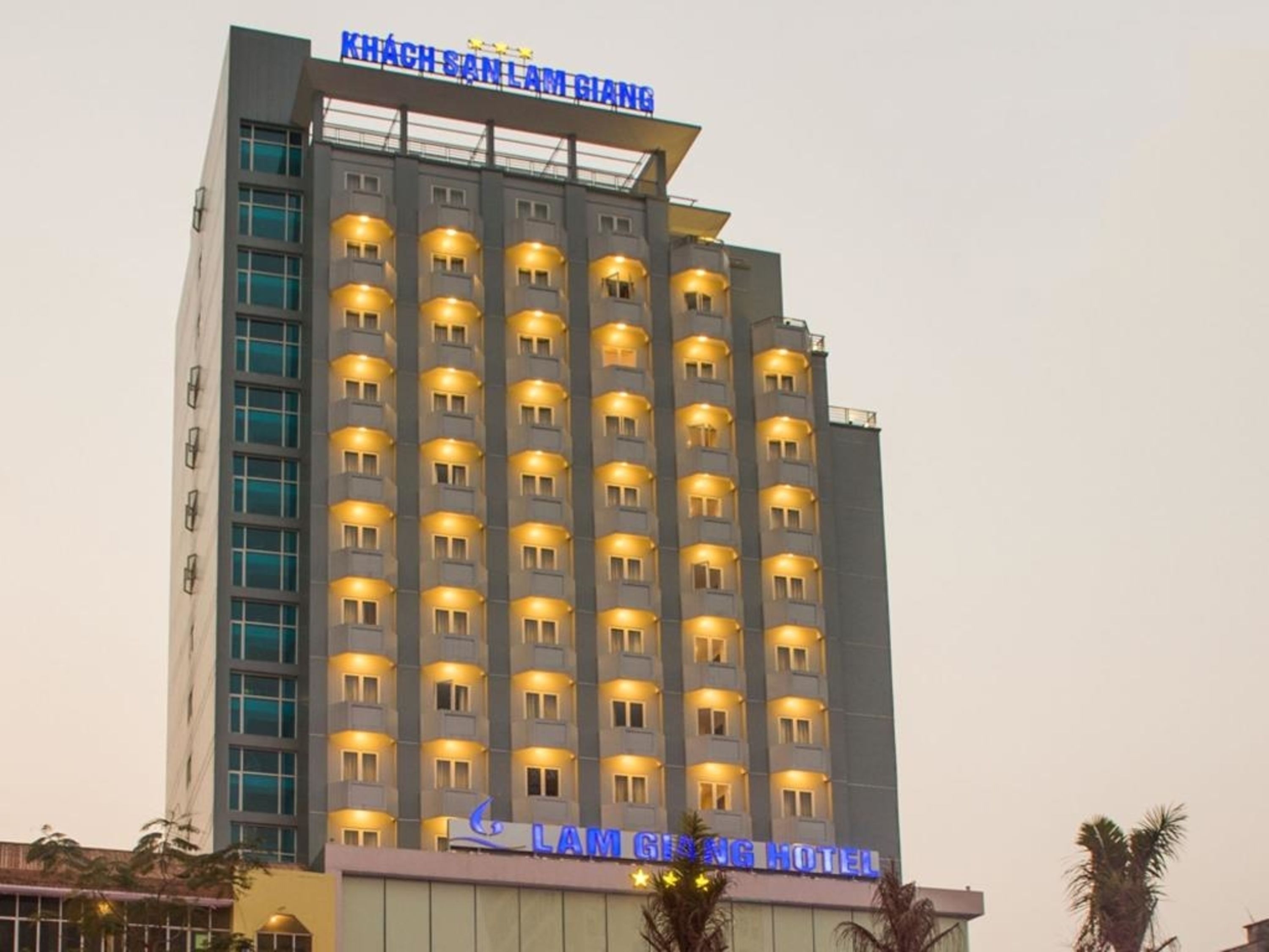 Un edificio de hotel de varios pisos con ventanas iluminadas y un letrero que dice "LAM GIANH HOTEL".