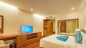 A hotel room with a bed, a TV on a wooden desk, a wardrobe, and a mirror. - Lam Giang Hotel (Thanh Vinh)